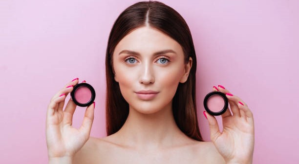 A beautiful woman with a radiant smile, showcasing pink blush on her cheeks, complemented by a subtle bronzer glow.