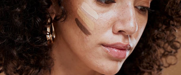 A woman with a brown complexion and brown eyes, showcasing flawless skin enhanced by foundation and concealer.