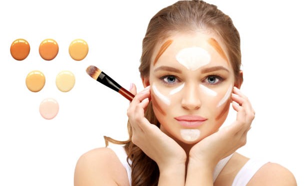 A woman applying highlighter and contour makeup with a brush, showcasing her artistry and beauty techniques.